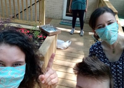 Three Atlanta Fellows from 2019-2020 wearing masks pose in the foreground while Mary Ann (also masked) poses in the background.