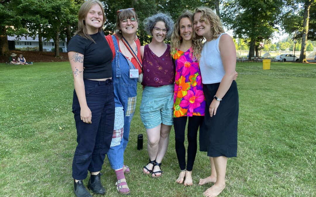 Five women standing shoulder to shoulder on a lawn.