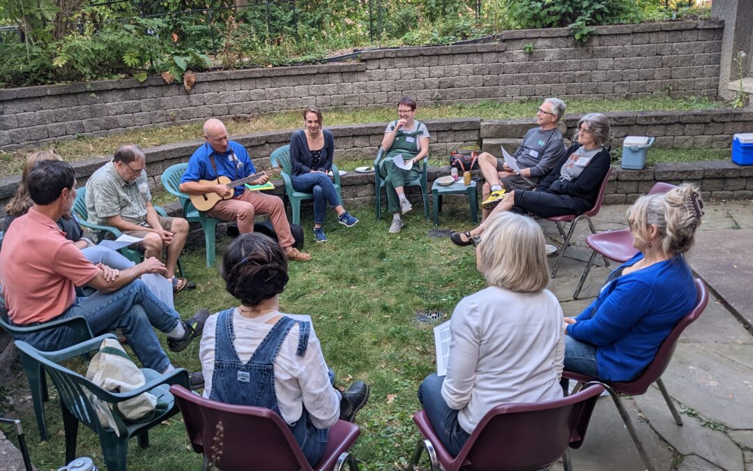 People sitting outside in a circle at a potluck.